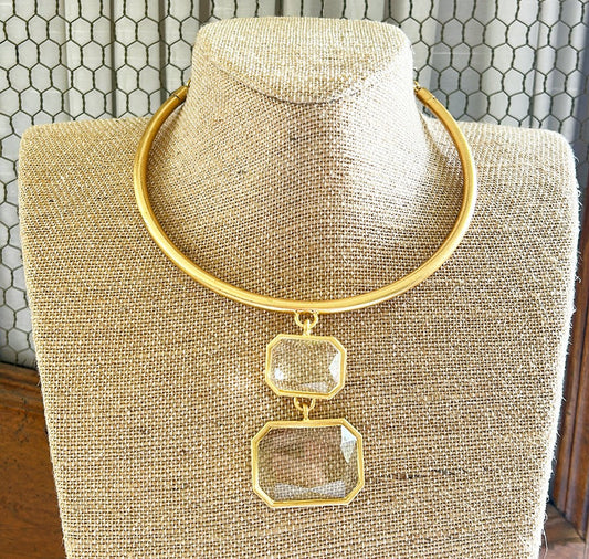 Simple gold metal collar style necklace with attached clear crystal style double pendant.