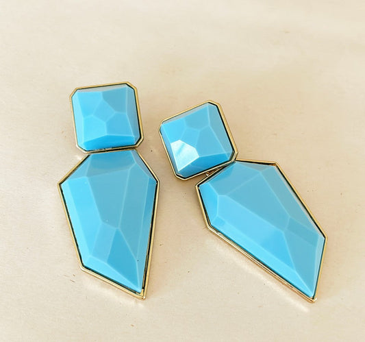 Extra large turquoise colored statement earrings set in a gold tone metal frame.